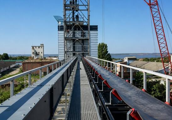 Belt conveyor and bucket elevator installed on the conveyor gallery of a grain handling facility
